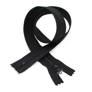 May include: A black zipper with a closed slider. The zipper is folded in half and the ends are overlapping.