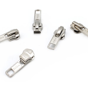 May include: Five silver zipper pulls with a rectangular pull tab and the text "YKK" on each.