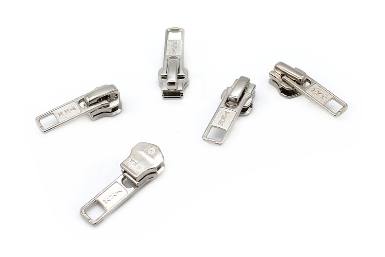 May include: Five silver zipper pulls with a rectangular pull tab and the text "YKK" on each.