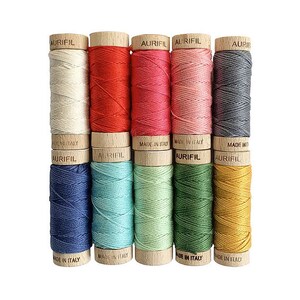 May include: A set of ten spools of thread in various colors, including white, red, pink, gray, blue, green, and yellow. Each spool is labeled "Aurifil" and "Made in Italy".