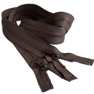 May include: A close-up of a brown zipper with two sliders. The zipper is coiled up and ready to be used for sewing or crafting projects.