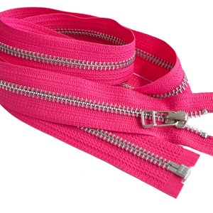 May include: A pink zipper with silver teeth and a silver slider. The zipper is folded in half and the slider is at the top of the zipper.