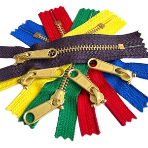 May include: Assortment of colorful zipper tapes with gold metal sliders. The zipper tapes are in red, green, blue, yellow, and purple.