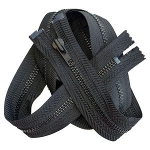 May include: A black coil zipper featuring a matching black metal slider pull. The zipper tape is made of a woven fabric, and the teeth are arranged in a continuous track. The slider is embossed with the letters YKK on its surface.