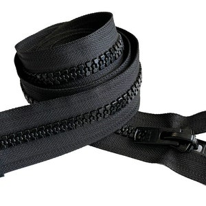 Puede incluir: Una cremallera negra con un deslizador negro. La cremallera está enrollada y lista para ser utilizada en proyectos de costura.