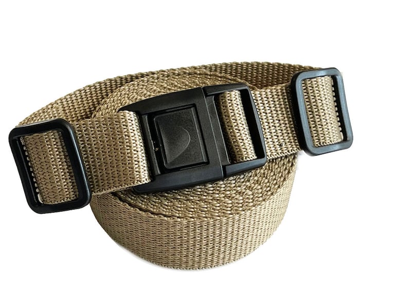 May include: A tan nylon strap with a black plastic buckle. The strap is rolled up and the buckle is visible.