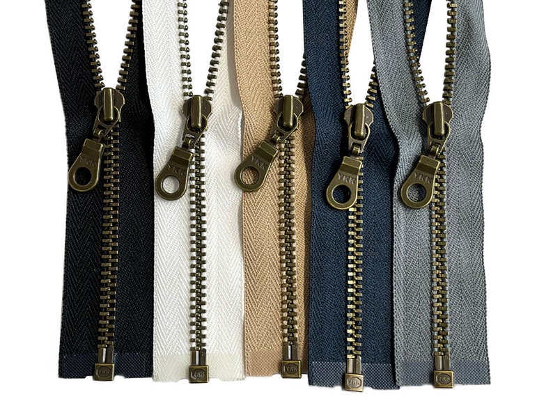 May include: Six different colors of zipper tape with antique brass zipper pulls. The zipper tape colors are black, white, beige, navy blue, gray, and light gray.
