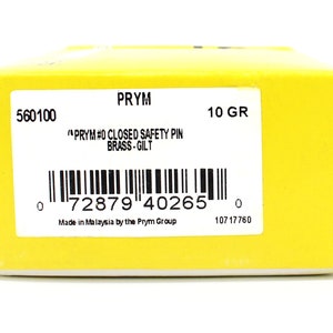 May include: A yellow box with a white label that reads "PRYM #0 CLOSED SAFETY PIN BRASS-GILT" and a barcode. The box also has the text "560100", "10 GR", "Made in Malaysia by the Prym Group", and "10717760".