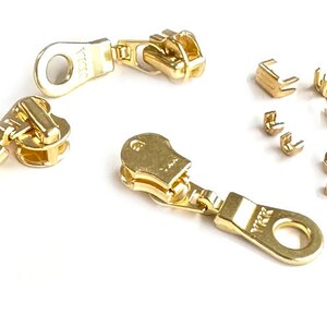 Puede incluir: Tiradores de cremallera de color dorado con la marca YKK y un juego de topes de cremallera de color dorado.