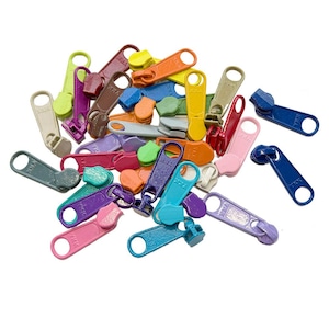May include: A collection of colorful zipper pulls in various shades, including pink, blue, green, yellow, and purple. The pulls are made of plastic and have a loop at one end for easy attachment. The image is taken from a top-down perspective.