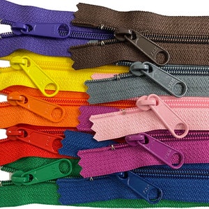 May include: A collection of colorful zippers in various shades, including purple, yellow, orange, red, green, blue, pink, and brown. Each zipper features a matching pull tab and a visible YKK logo.