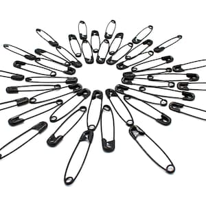 May include: A collection of black safety pins arranged in a circular pattern, radiating outwards from the center.