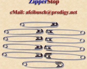 May include: Ten silver safety pins, each measuring approximately 1 inch in length, are arranged in two rows of five pins. A ruler is visible at the bottom of the image, with markings for inches.