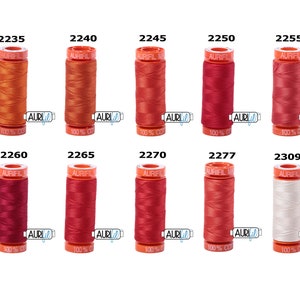 May include: A collection of ten spools of Aurifil thread in various shades of red, orange, and white. The spools are labelled with their corresponding numbers: 2235, 2240, 2245, 2250, 2255, 2260, 2265, 2270, 2277, and 2309.