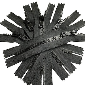 May include: A close-up of a group of black zippers arranged in a circular pattern. The zippers are all closed and have a metal slider.