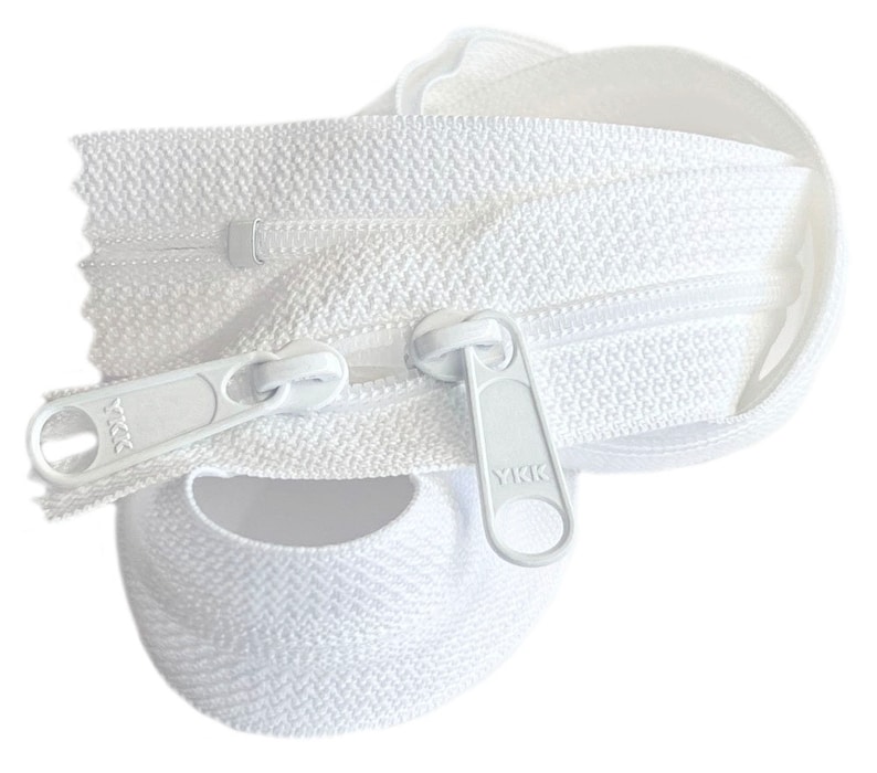 May include: White zipper tape with a white zipper pull. The zipper pull has the text "YKK" on it.