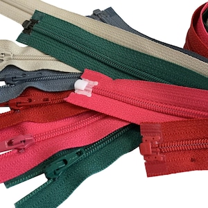 May include: Assortment of zipper tapes in various colors, including red, pink, green, beige, and gray. The zippers are all closed and have a metal slider.