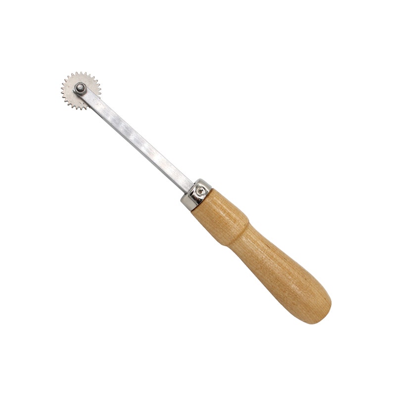 May include: A silver rotary cutter with a wooden handle. The cutter has a circular blade with a small metal knob in the center.