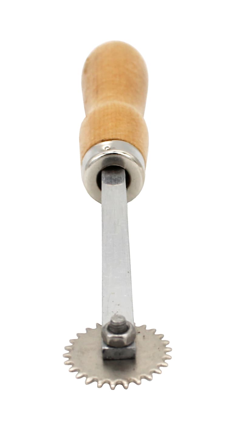 May include: A silver rotary cutter with a wooden handle. The cutter has a circular blade with a serrated edge.