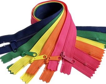 Puede incluir: Un conjunto de diez cremalleras de colores en varios colores, incluyendo azul marino, verde, amarillo, naranja y rosa. Las cremalleras están dispuestas en forma de abanico, con los tiradores de las cremalleras visibles.