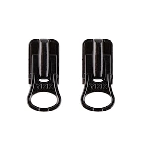 Peut inclure: Deux tirettes de fermeture éclair noires avec un logo YKK. Les tirettes sont en métal et ont une boucle en bas.