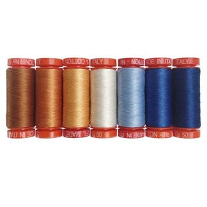 May include: Eight spools of thread in various shades of brown, blue, and white. The spools are labeled "Made in Italy" and have a red and white label.