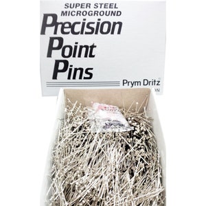 May include: A box of Prym Dritz Super Steel Microground Precision Point Pins. The box is white with black text and the pins are silver.