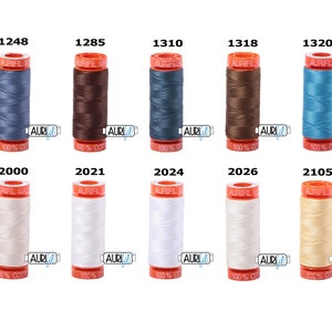 May include: Ten spools of Aurifil thread in various colours, including blue, brown, white, and beige. Each spool is labelled with the Aurifil logo and the thread number.
