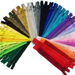 May include: A rainbow assortment of 20 zipper closures in various colors, including red, orange, yellow, green, blue, purple, and pink. The zippers are arranged in a fan shape, with the red zippers at the bottom and the pink zippers at the top.