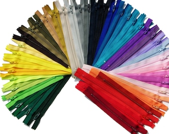 Puede incluir: Un surtido arcoíris de 20 cierres de cremallera en varios colores, incluyendo rojo, naranja, amarillo, verde, azul, morado y rosa. Las cremalleras están dispuestas en forma de abanico, con las cremalleras rojas en la parte inferior y las cremalleras rosas en la parte superior.