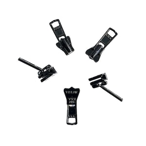 May include: Five black metal zipper pulls. One pull has the text "VISLON YKK SWISS" on it.