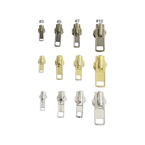 May include: Assortment of metal zipper pulls in gold, silver, and bronze finishes. The pulls are labeled with numbers 3, 5, 7, and 10. Each pull features the YKK logo.