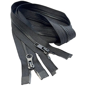May include: Close-up of several black zippers with metal pulls. The zippers are arranged in a curved pattern, showcasing the teeth and the fabric tape. The pulls are in the closed position.
