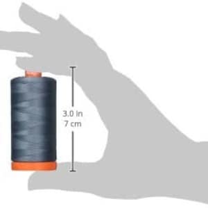 May include: A spool of dark gray thread with an orange bobbin, measuring 3 inches or 7 centimeters in height.