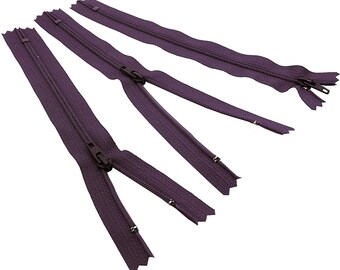 Op de afbeelding: Drie paarse ritsen met zwarte treklipjes. De ritsen zijn ongeveer 25 cm lang.