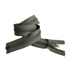 Puede incluir: Una cremallera verde con un tirador negro. La cremallera está enrollada y lista para ser utilizada en proyectos de costura.