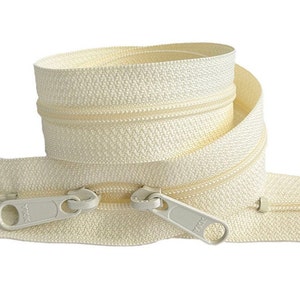 May include: A close-up of a white zipper tape with two silver zipper pulls. The zipper tape is coiled and the zipper pulls are visible at the bottom of the image.