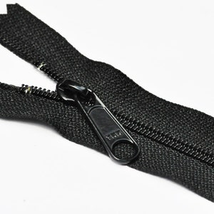 May include: Black zipper with a black plastic slider. The zipper is open and the slider is in the middle of the zipper.