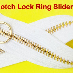 Pode incluir: Um z&iacute;per branco com um cursor de metal dourado e um puxador de anel. O z&iacute;per tem uma fun&ccedil;&atilde;o de trava de entalhe. O texto "Notch Lock Ring Slider" est&aacute; escrito em vermelho acima do z&iacute;per.