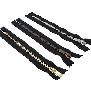 May include: Three black zipper tapes with different colored metal zipper pulls. The zipper pulls are gold, silver, and bronze.