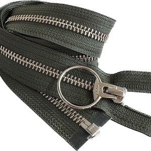 May include: A close-up of a green zipper with a silver metal slider and pull tab. The zipper is made of nylon and has a textured finish. The zipper is a YKK brand zipper.