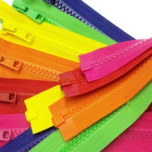 May include: A collection of colorful zipper tapes in various colors, including pink, green, yellow, orange, red, and blue. The zippers are arranged in a fan shape, with the ends of the tapes overlapping.