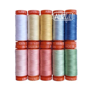 May include: A set of 10 spools of Aurifil thread in various pastel colors, including pink, blue, green, and yellow. The spools are labeled "100% Cotton" and "Made in Italy".