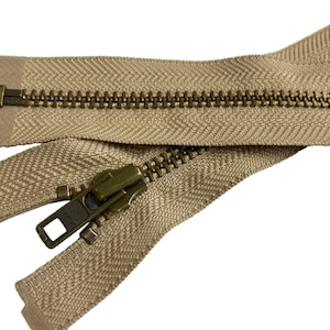 May include: A beige zipper with a brass slider and pull. The zipper is open and the teeth are visible.