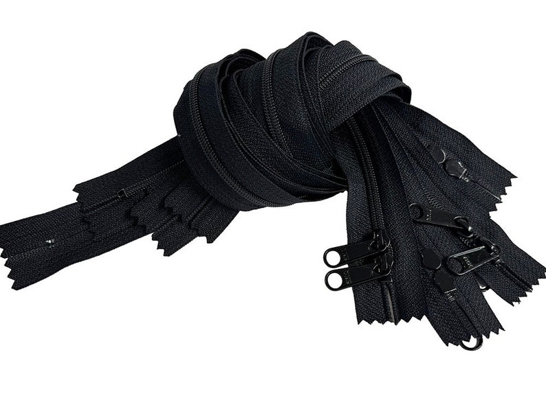 May include: A bundle of black zipper tape with black metal sliders. The zipper tape is folded and tied together in a knot.