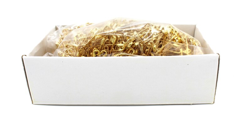 May include: A white box filled with a clear plastic bag of gold safety pins.