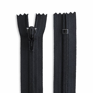 May include: A black zipper with a black slider and a black pull tab. The zipper is open and the slider is in the middle of the zipper.