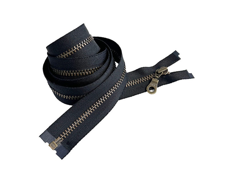 May include: A black zipper with a brass slider and pull. The zipper is coiled up and ready to be used for sewing projects.