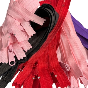 May include: A collection of colorful zippers in various shades, including pink, black, red, and purple. The zippers are arranged in a close-up shot, showcasing the zipper pulls and teeth. These are likely for sewing and crafting projects.
