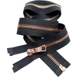 May include: A continuous black zipper tape featuring metallic rose gold teeth and a matching rose gold slider pull. The zipper is coiled in a circular arrangement, showcasing the contrast between the dark fabric tape and the shiny metal elements.